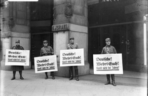 Israel's Department Store in Berlin on April 1, 1933 at the start of the Nazi boycott of Jewish-owned businesses. These are members of the SA (Sturmabteilung) holding placards that say: "Germans defend yourselves! Don't buy from Jews." (Source: Wikimedia Commons/Bundesarchiv Bild 102-14469)