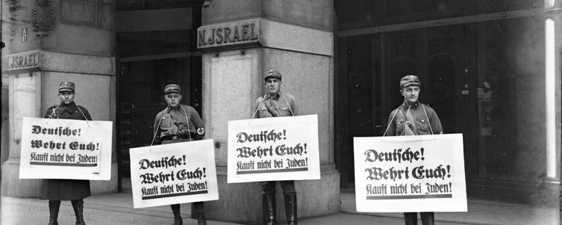 Israel's Department Store in Berlin on April 1, 1933 at the start of the Nazi boycott of Jewish-owned businesses. These are members of the SA (Sturmabteilung) holding placards that say: "Germans defend yourselves! Don't buy from Jews." (Source: Wikimedia Commons/Bundesarchiv Bild 102-14469)