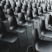 Large group of empty black chairs in a conference room