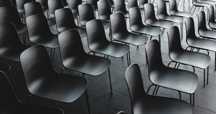 Large group of empty black chairs in a conference room