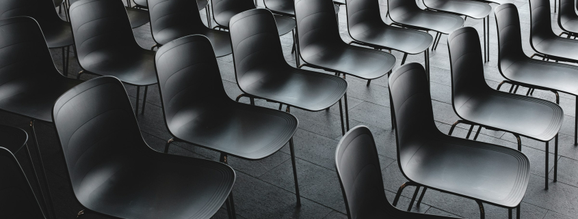 Large group of empty black chairs in a conference room
